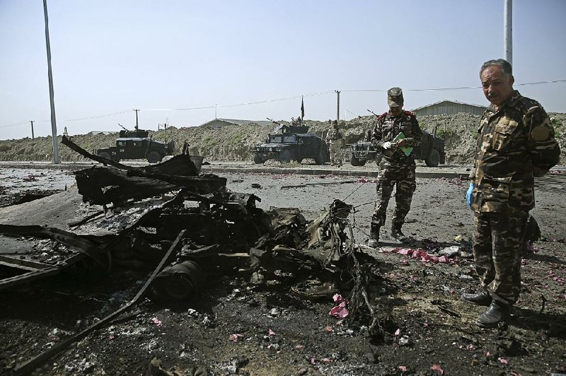 Afghan security forces inspect the site of a suicide attack near a building which Taliban fighters used during a clash with security forces, in Kabul, Afghanistan, Thursday, July 17, 2014. Gunmen launched a pre-dawn attack on the Kabul International Airport in the Afghan capital on Thursday, raining down rockets on the sprawling facility, setting off a gunbattle with security forces and forcing the airport to close, officials said.  The attack comes during a tense time in Afghanistan, as a recount is underway from the disputed second round of a presidential election seen as key to insuring a peaceful transfer of power ahead of the withdrawal of foreign troops by the end of the year.  (AP Photo/Massoud Hossaini)