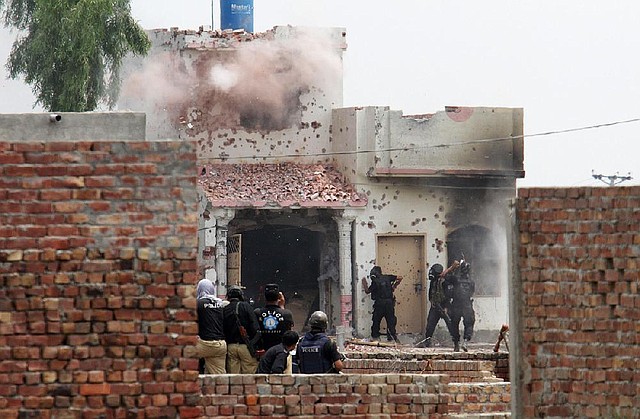 Pakistani police commandos carry out an operation at a militant hideout in Lahore, Pakistan, Thursday, July 17, 2014. Officials said police fought for more than 10 hours with militants planning to attack the prime minister's home in eastern Pakistan. (AP Photo/K.M. Chaudary)