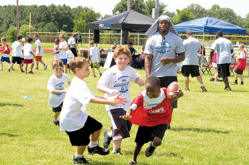 ProCamp participants run with the football after catching a pass from Carolina Panthers running back Jonathan Stewart.
