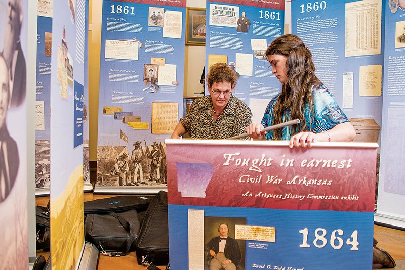 Lynita Langley-Ware, left, with help from her daughter Sophia, sets up one of the panels of a traveling Civil War exhibit at the Faulkner County Museum in Conway.