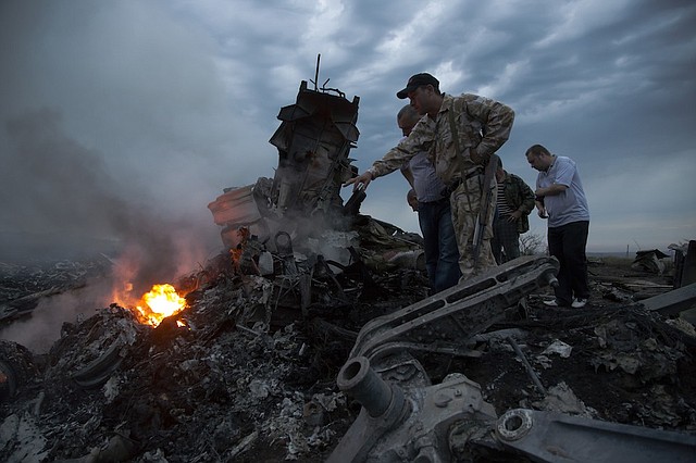 People inspect the crash site of a passenger plane near the village of Hrabove, Ukraine, on Thursday, July 17, 2014. Ukraine said a passenger plane was shot down Thursday as it flew over the country, and both the government and the pro-Russia separatists fighting in the region denied any responsibility for downing the plane. 