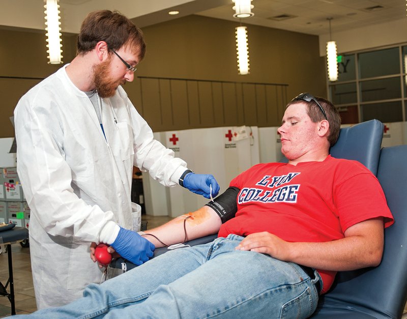 Phlebotomist Shane Mathes, left, checks the cuff on the arm of Nate Ayers while he gives blood in Edwards Commons at Lyon College.
