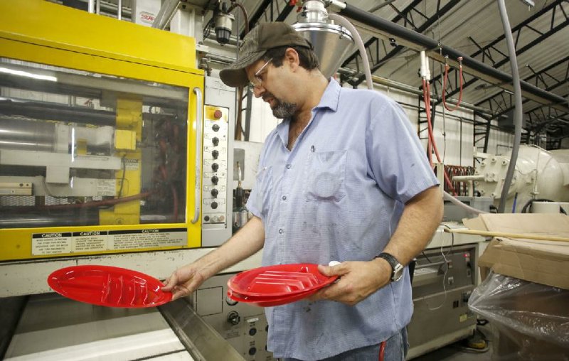 NWA Media/DAVID GOTTSCHALK 7/14/14 - Steven King, A Shift (cq, this is the name of the shift) supervisor at PolyTech Molding Inc. in Prairie Grove, examines a new The Taco Plate manufactured in a injection molding machine at the plant Monday July 14, 2014.