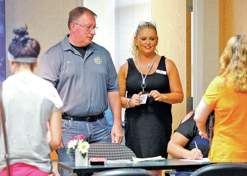 STAFF PHOTO JASON IVESTER Lynn and Tammy Hahn watch as participants register and pay the fee June 14 for a Mothers Against Drunk Driving class at the Rogers Police Department. The class is required for those arrested for driving while intoxicated.