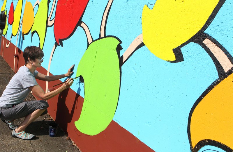 The Sentinel-Record/Richard Rasmussen PARKING LOT ART: Decorative artist Sheila Roscoe, of Hot Springs, works on a mural with other area artists in a parking lot on Central Avenue on Tuesday. The mural was designed by Gary Simmons, a local artist.