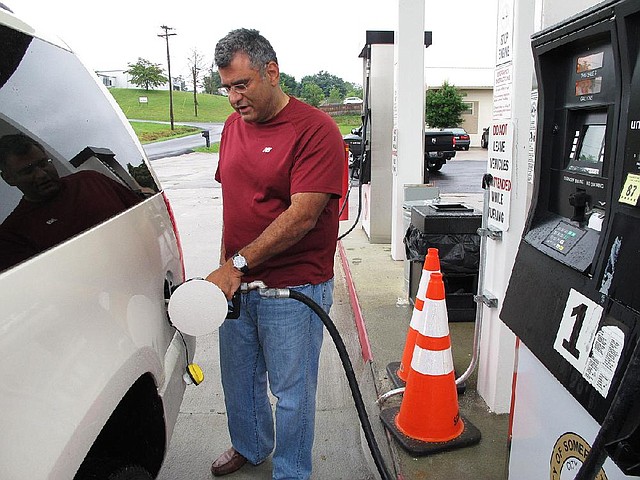 Samir Cook fills up his vehicle at a city-run station on Saturday, July 19, 2014, in Somerset, Ky. The station on the outskirts of Somerset opened to the public on Saturday, selling regular unleaded gas for $3.36 a gallon. In the first three hours, about 75 customers fueled up at the no-frills city station, where there are no snacks, no repairs and only regular unleaded gas. The city’s mayor says he hopes the no-frills station will lower gas prices around town. (AP Photo/Bruce Schreiner)