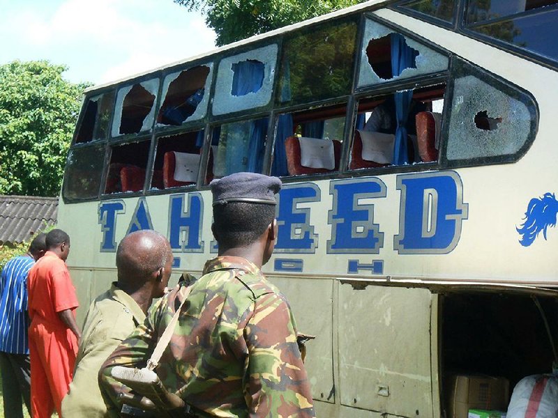 A Kenyan police officer with civilians watch the Taheed Bus at the Lamu Police Station, Saturday, July 19, 2014. The Kenya Red Cross says seven people have been killed after gunmen attacked a bus along the Kenyan coast where previous attacks had left 87 people dead. The humanitarian group said Saturday the attack Friday night came at Corner Mbaya, 5 kilometers (3 miles) from the coastal town of Witu. Al-Qaida-linked al-Shabab militants from Somalia claimed responsibility for the attack. (AP Photo)