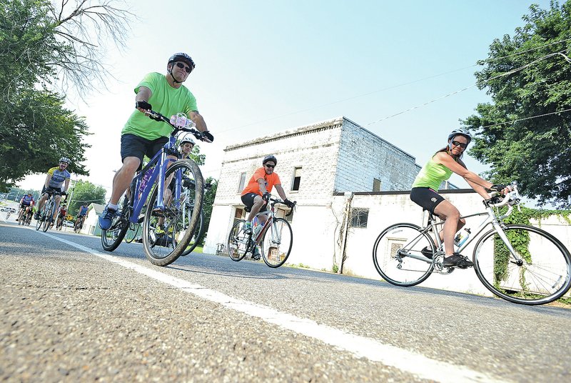 STAFF PHOTO SAMANTHA BAKER @NWASAMANTHA Cyclists head off on bicycle tours Saturday on South Main Street in Cave Springs during the first Tour de Cave tour.