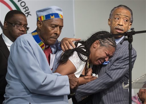 Esaw Garner, center, wife of Eric Garner, breaks down in the arms of Rev. Herbert Daughtry and Rev. Al Sharpton, right, during a rally at the National Action Network headquarters for Eric Garner, Saturday, July 19, 2014, in New York. Garner, 43, died Thursday, during an arrest in Staten Island, when a plain-clothes police officer placed him in what appeared be a chokehold while several others brought him to the ground and struggled to place him in handcuffs.