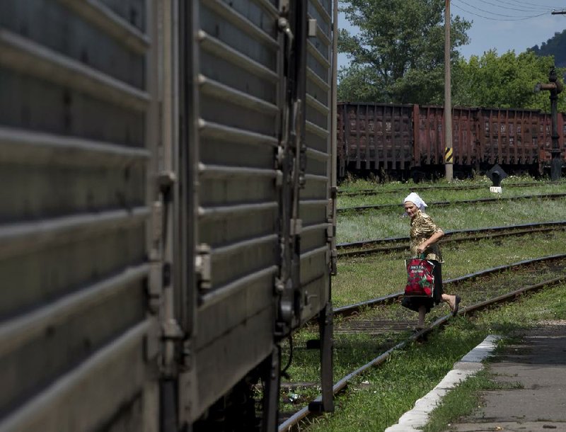 A woman looks at a refrigerated train loaded with the bodies of victims, in Torez, eastern Ukraine, 15 kilometers (9 miles) from  the crash site of Malaysia Airlines Flight 17, Sunday, July 20, 2014. Armed rebels forced emergency workers to hand over all 196 bodies recovered from the Malaysia Airlines crash site and had them loaded Sunday onto refrigerated train cars bound for a rebel-held city, Ukrainian officials and monitors said. (AP Photo/Vadim Ghirda)