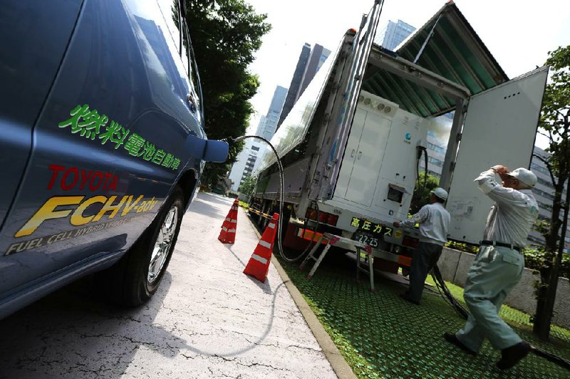 In this July 14, 2014 photo, a Toyota fuel cell hybrid vehicle is refueled from a mobile hydrogen station at the Ministery of Economy, Trade and Industry in Tokyo.  Toyota’s still-to-be-officially-named vehicle goes on sale in Japan sometime before April 2015, and within a half year after that in the U.S. and Europe.  Apart from cost, the other big drawback is lack of hydrogen fueling stations. Only about 30 of them exist throughout Japan so far, although the government is leading a push to get more built in coming months. Lack of charging stations is also a weakness for electric cars but there are fewer obstacles to establishing and supplying that infrastructure because electricity networks are already in place. (AP Photo/Eugene Hoshiko)