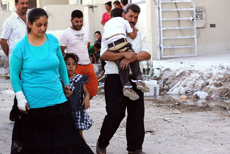 In this Saturday, July 19, 2014 photo, displaced Christians who fled the violence in Mosul, walks towards the town of Qaraqoush on the outskirts of Mosul, Iraq. The message played over loudspeakers gave the Christians of Iraq's second-largest city until midday Saturday to make a choice: convert to Islam, pay a tax or face death. By the time the deadline imposed by the Islamic State extremist group expired, the vast majority of Christians in Mosul had made their decision. They fled. (AP Photo)