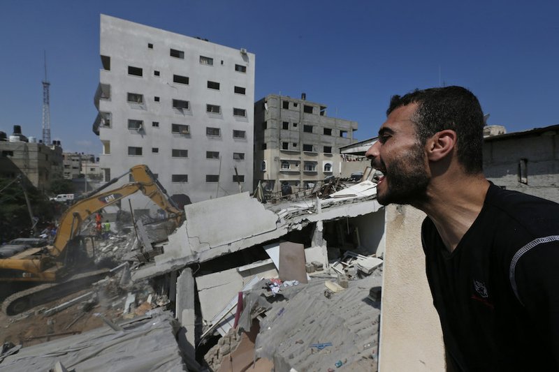 A Palestinian gives instructions as he watches rescuers searching for bodies and survivors under the rubble of an apartment building, destroyed by an Israeli missile strike, in Gaza City on Monday, July 21, 2014. 
