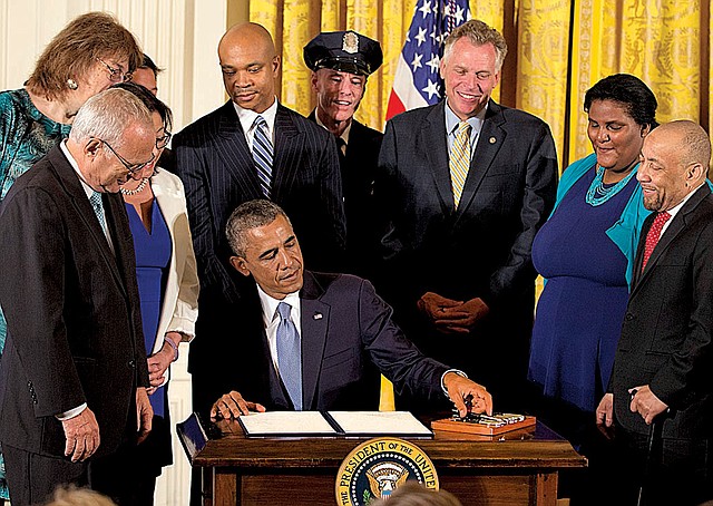 President Barack Obama, surrounded by gay-rights supporters including Virginia Gov. Terry McAuliffe (third from right), signs executive orders in the East Room of the White House on Monday to protect gay employees from federal workplace discrimination.