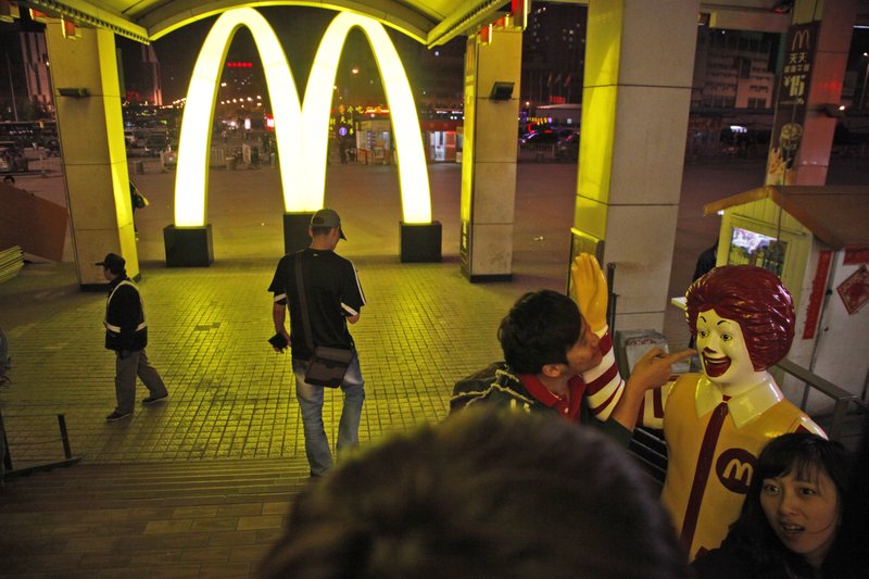 In this photo taken Saturday, May 21, 2011, a Chinese man poses for photos with Ronald McDonald, the mascot for fast food restaurant McDonald's outside one of its branch at a train station in Shenyang in northern China's Liaoning province.  McDonalds and KFC in China faced a new food safety scare Monday, July 21, 2014 after a Shanghai television station reported a supplier sold them expired beef and chicken.