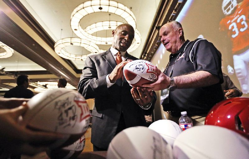 Texas head coach Charlie Strong, left, signs footballs for Peter Irwin at the Big 12 Conference NCAA college football media days in Dallas, Tuesday, July 22, 2014. (AP Photo)