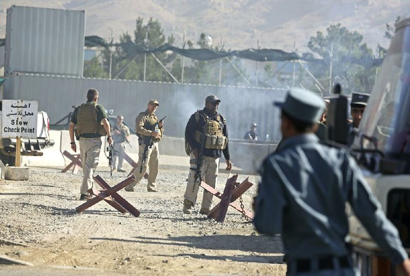 Afghan and foreign security forces inspect the site of a suicide attack at the deputy counter narcotic compound in Kabul, Afghanistan, Tuesday, July 22, 2014. An Afghan official said that four security guards were killed and six others wounded after a suicide bomber on a motorbike carried out the attack  (AP Photo/Rahmat Gul)