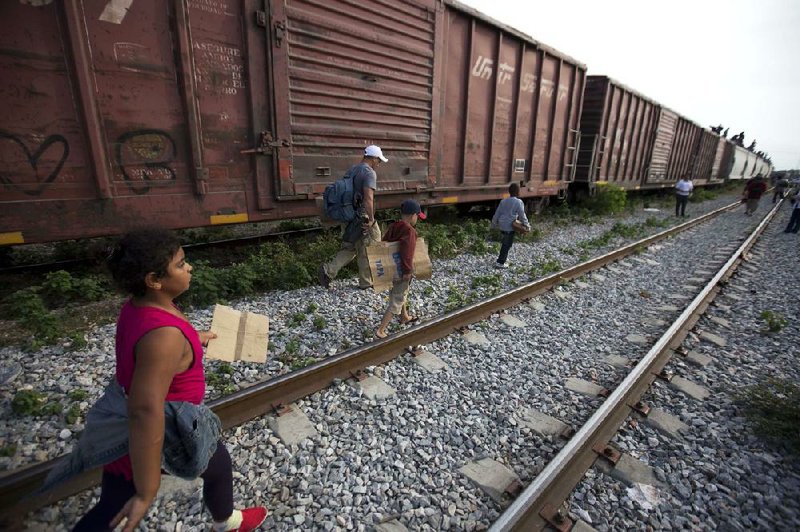 In this July 12, 2014, photo, migrants walk along the rail tracks after getting off a train during their journey toward the U.S.-Mexico border in Ixtepec, Mexico. The surge in unaccompanied minors and women with children migrating from Central America has put new attention on decades-old smuggling organizations.  (AP Photo/Eduardo Verdugo)