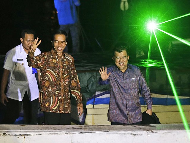 Indonesian president-elect Joko Widodo, left, and vice president-elect Jusuf Kalla gesture to the media after delivering their victory speech, on a traditional phinisi ship at Sunda Kelapa port  in Jakarta, Indonesia, Tuesday, July 22, 2014. Jakarta Gov. Joko Widodo, who captured the hearts of millions of Indonesians with his common man image, won the country's presidential election with 53 percent of the vote, final results showed Tuesday. (AP Photo/Dita Alangkara)