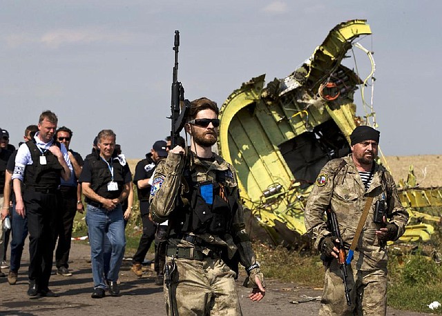 Pro-Russian rebels, right, followed by members of the OSCE mission, walk by plane wreckage as they arrive for a media briefing at the crash site of Malaysia Airlines Flight 17, near the village of Hrabove, eastern Ukraine, Tuesday, July 22, 2014. A team of Malaysian investigators visited the site along with members of the OSCE mission for the first time since last week's crash. (AP Photo/Vadim Ghirda)