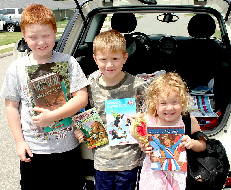 LYNN KUTTER Isaac Tustin, 8, left, Titus Tustin, 6, and Brinly Tustin, 4, are excited about their free books to take home and read.