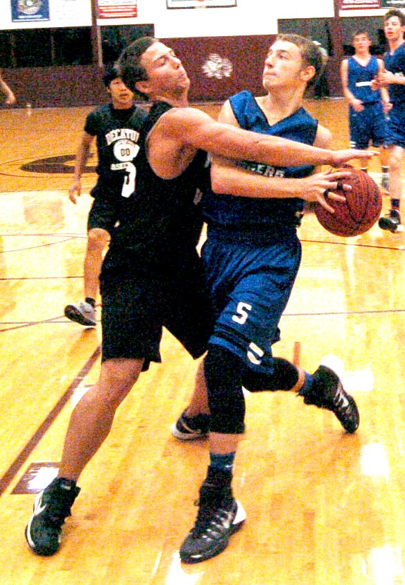 Photo by Mike Eckels Victor Urquidi, Decatur guard, throws a block that prevents a Rogers player from attempting a layup. The Mounties defeated the Bulldogs during play in the Gentry Summer Basketball League July 17 at Gentry High School Gym.