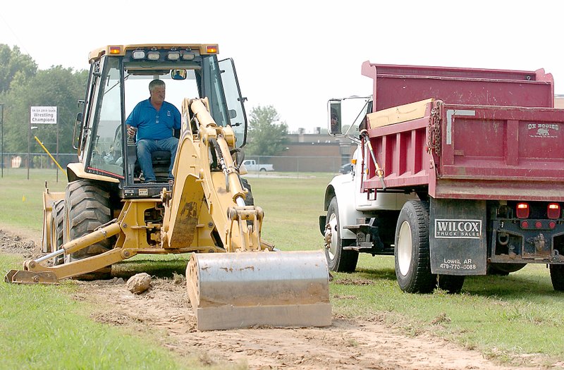 Photo by Randy Moll Laymon Donohew operates the backhoe and Jeremy McJunkin assisted in the dump truck on Monday as Gentry city crews prepared to build a new sidewalk along the west side of school property on Pioneer Lane.