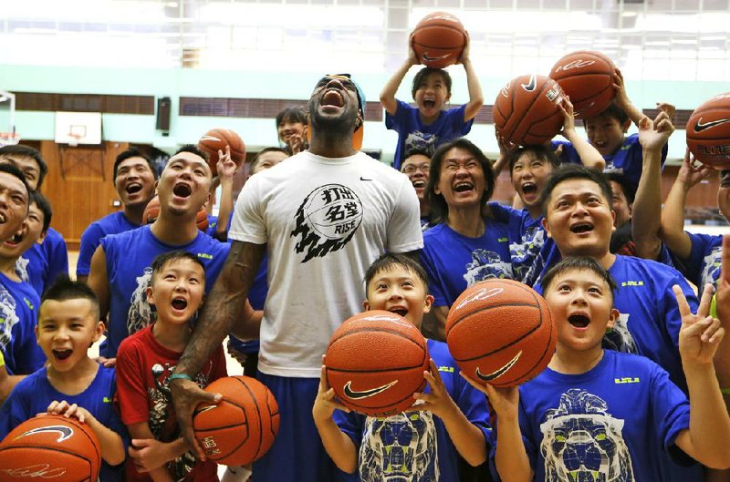 NBA star LeBron James poses with his fans during a basketball clinic in Hong Kong as part of his China tour Wednesday, July 23, 2014. Earlier this month, James left the Miami Heat after four seasons and four trips to the NBA Finals and re-signed with the Cavaliers, where his career began. (AP Photo/Kin Cheung)