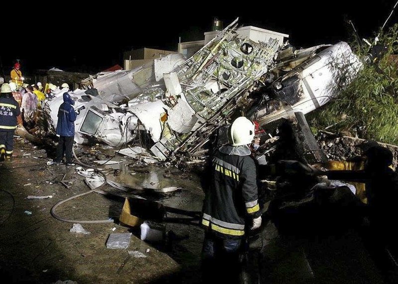 Rescue workers survey the wreckage of TransAsia Airways flight GE222 which crashed while attempting to land in stormy weather on the Taiwanese island of Penghu, late Wednesday, July 23, 2014. A transport minister said dozens of people were trapped and feared dead. (AP Photo/Wong Yao-wen)