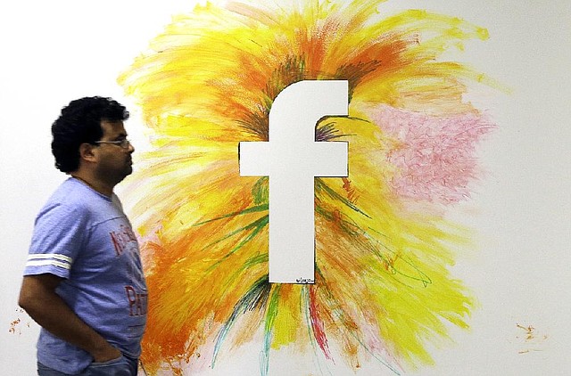 In this June 11, 2014 photo, a man walks past a Facebook logo in an office on the Facebook campus in Menlo Park, Calif. Facebook reports quarterly financial results on Wednesday, July 23, 2014.(AP Photo/Jeff Chiu)