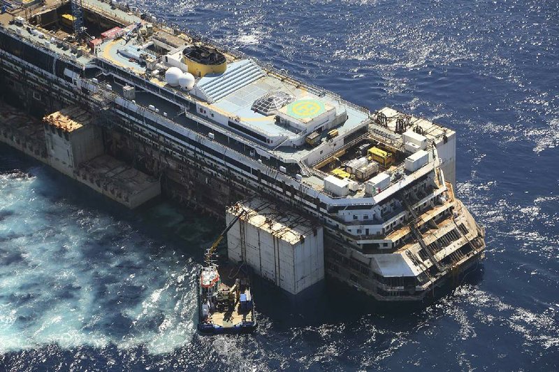 In this aerial picture provided by the Italian Civil Protection Department, the wreck of the Costa Concordia is towed by two tugboats as it leaves behind the tiny Tuscan island of Isola del Giglio,  Italy, Wednesday, July 23, 2014. The Costa Concordia cruise liner has begun its final voyage away from the tiny Italian island where it capsized on Jan. 13, 2012, killing 32 people. (AP Photo/Courtesy of the Italian Civil Protection Department, ho)