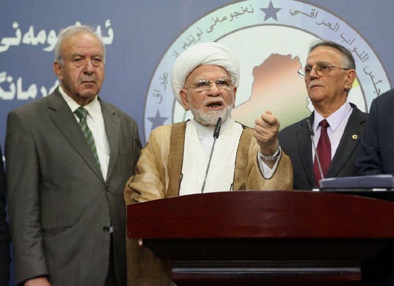 Shiite lawmaker Mohammad Taqi al-Mawla, center, speaks to the media in Baghdad, Iraq, Wednesday, July 23, 2014. Iraq's parliament convened to vote for a new president on Wednesday. Since 2003, Iraq's political parties have agreed to assign the position of president to a Kurd, prime minister to a Shiite and speaker of parliament to a Sunni. The next president will task someone with forming a new government, and whoever can assemble a majority coalition will become the next prime minister. (AP Photo/Karim Kadim)