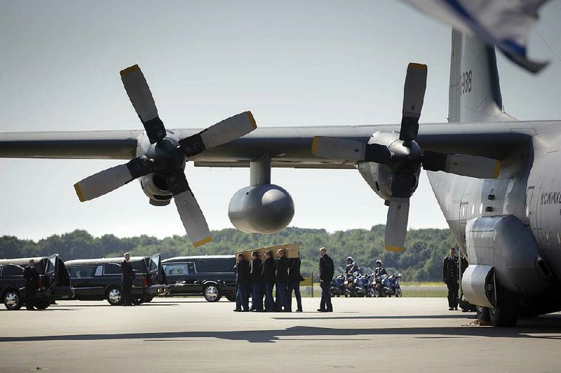 Pallbearers carry a coffin out of a military transport plane towards a hearse during a ceremony to mark the return of the first bodies, of passengers and crew killed in the downing of Malaysia Airlines Flight 17, from Ukraine at Eindhoven military air base, Netherlands, Wednesday, July 23, 2014. After being removed from the planes, the bodies are to be taken in a convoy of hearses to a military barracks in the central city of Hilversum, where forensic experts will begin the painstaking task of identifying the bodies and returning them to their loved ones. (AP Photo/Phil Nijhuis)