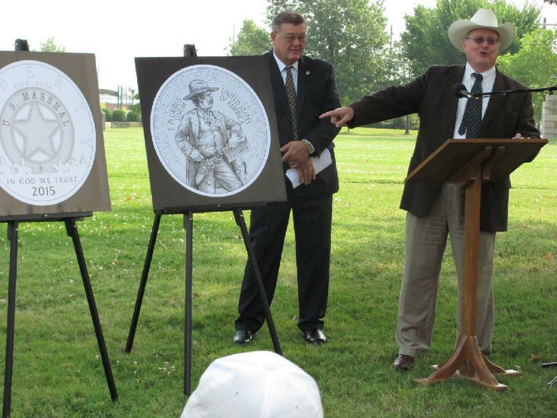 Arkansas Democrat-Gazette/DAVE HUGHES
Marshals Museum Board of Directors Chairman Jim Spears, right, points to scroll in marshal's hand saying "Wanted in Fort Smith" on the face of the silver coin design unveiled Wednesday in Fort Smith and Washington, D.C., to commemorate the U.S. Marshals Service 225 anniversary. Western Arkansas U.S. Marshal Mike Oglesby, center, unveiled the renderings of the gold, silver and clad coins.