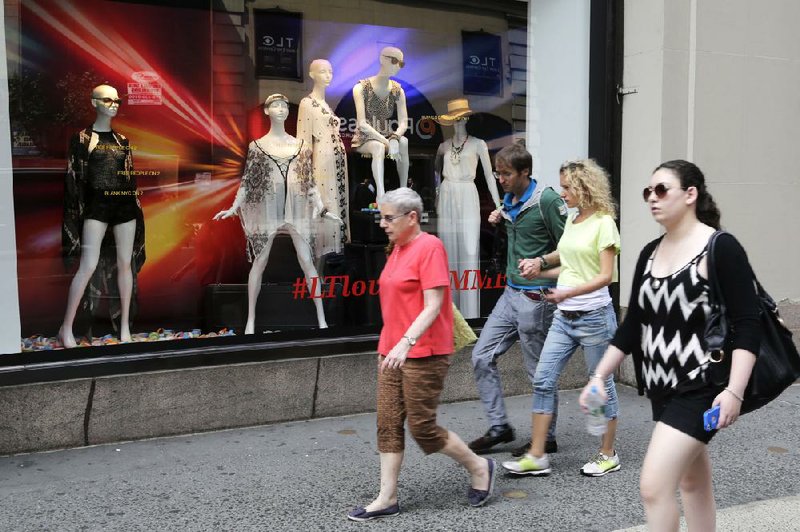 People walk past a window display of spring and summer fashions at Lord & Taylor department store, Monday, July 21, 2014 in New York. (AP Photo/Mark Lennihan)
