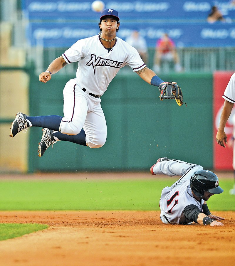  STAFF PHOTO SAMANTHA BAKER @NWASAMANTHA Cheslor Cuthbert, left, of the Northwest Arkansas Naturals leaps over Adam Melker of the Arkansas Travelers while making a play to first base Wednesday at Arvest Ballpark in Springdale.