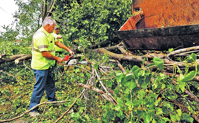 STAFF PHOTO JASON IVESTER Phil Frost, left, and Dan Howell, both Rogers Street Department employees, cut through downed trees Wednesday on Eighth Street after a storm passed through Northwest Arkansas bringing strong wind and rain.