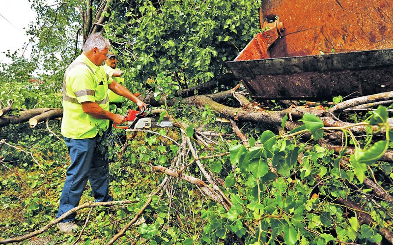 STAFF PHOTO JASON IVESTER Phil Frost, left, and Dan Howell, both Rogers Street Department employees, cut through downed trees Wednesday on Eighth Street after a storm passed through Northwest Arkansas bringing strong wind and rain.