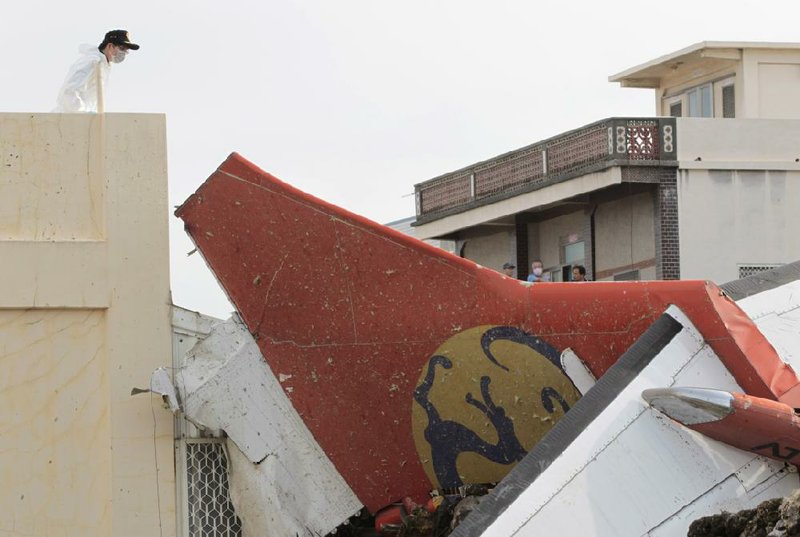 A special investigator inspects the tail wing of crashed TransAsia Airways flight GE222 on the outlying island of Penghu, Taiwan, Thursday, July 24, 2014. Stormy weather on the trailing edge of Typhoon Matmo was the likely cause of the plane crash that killed more than 40 people, the airline said Thursday. (AP Photo/Wally Santana)