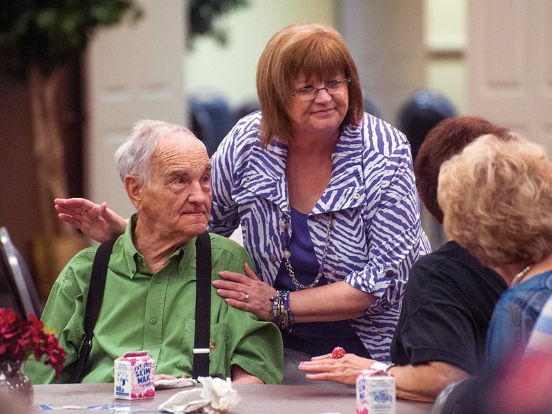 Paulette Womack, center, pats Bobby Green on the shoulder during the grand opening Wednesday of the Conway Senior Wellness and Activity Center. Green was celebrating his 86th birthday by eating lunch at the center in its new location on Siebenmorgen Road.