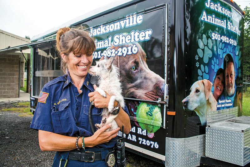 Hedy Wuelling, Jacksonville Animal Control manager, holds one of the shelter’s dogs in front of the new mobile adoption trailer.