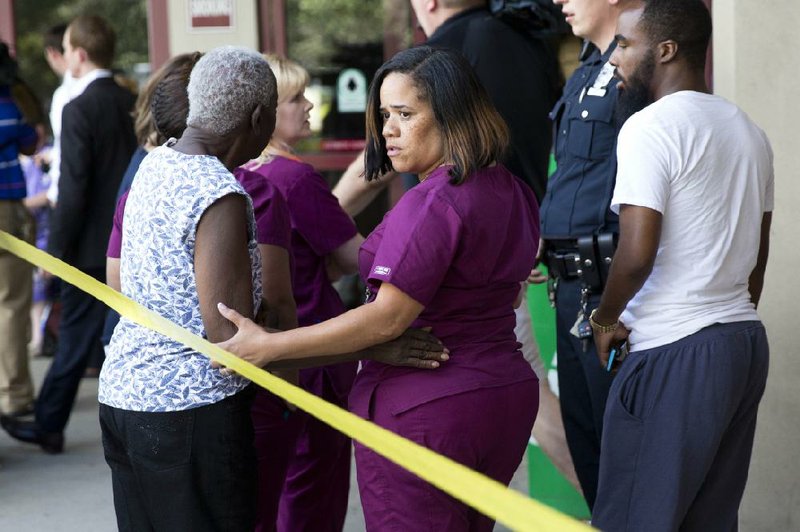 A hospital worker views police activity near the scene of a shooting at a wellness center attached to Mercy Fitzgerald Hospital in Darby, Pa., on Thursday, July 24, 2014. A doctor grazed by gunfire from a patient who had entered his office in a suburban hospital's psychiatric unit stopped him by returning fire with his own gun and injuring him, authorities said. (AP Photo)