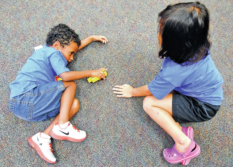 STAFF PHOTO JASON IVESTER Miles Harmon, 5, left, and Abbie Clements, 9, play with a toy bus on the floor during Camp Connect.