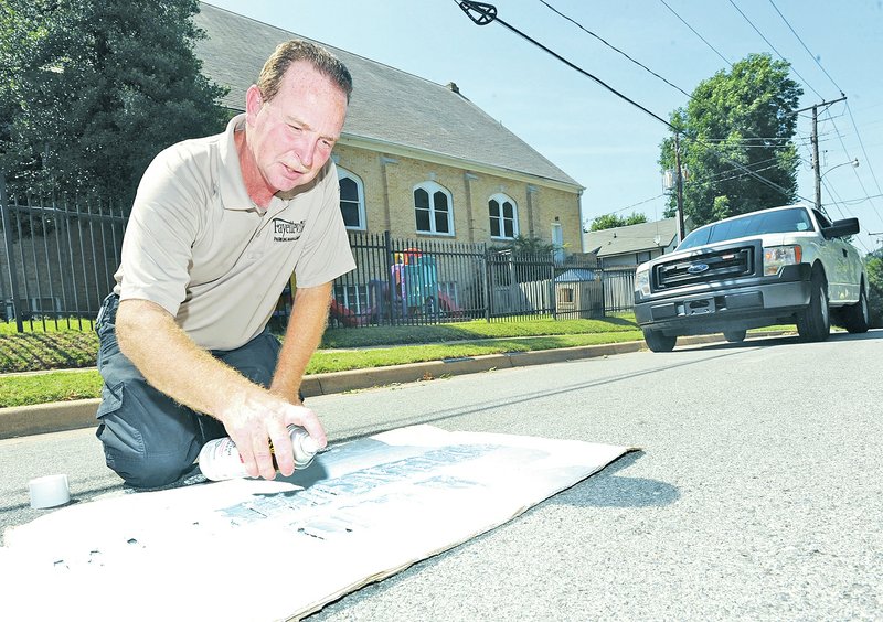 STAFF PHOTO ANDY SHUPE Darrin Wright paints new markings on parking spaces on Locust Avenue in Fayetteville.