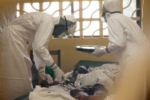 In this 2014 photo provided by the Samaritan's Purse aid organization, Dr. Kent Brantly, left, treats an Ebola patient at the Samaritan's Purse Ebola Case Management Center in Monrovia, Liberia. On Saturday, July 26, 2014, the North Carolina-based aid organization said Brantly tested positive for the disease and was being treated at a hospital in Monrovia.