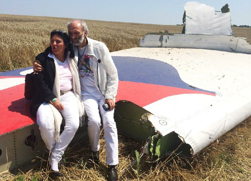 Jerry Dyczynski and Angela Rudhart-Dyczynski, whose daughter Fatima was killed when a Malaysian Airlines plane was shot down over Ukraine, sit on part of the wreckage Saturday in Hrabove. The couple from Perth, Australia, crossed territory held by pro-Russian rebels to reach the crash site.