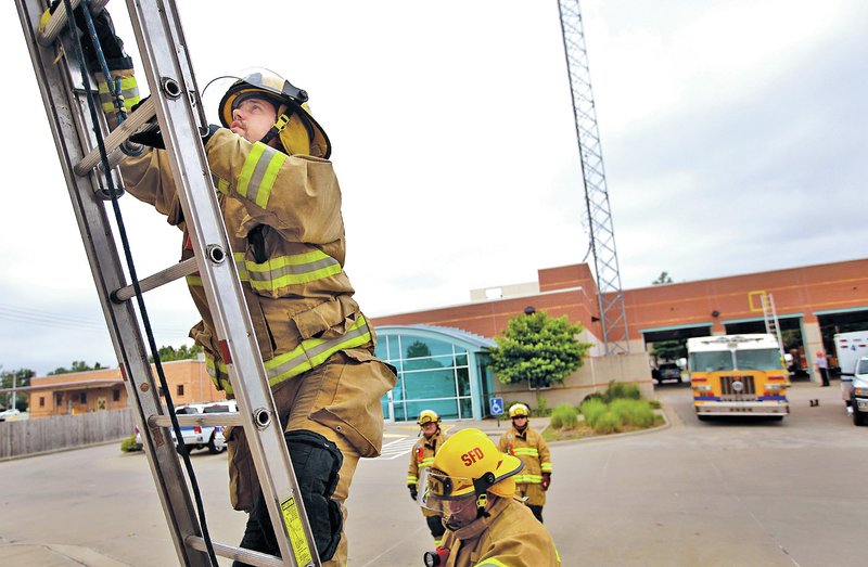 STAFF PHOTO JASON IVESTER Firefighter Joe Sabatini ascends a ladder during training Thursday in Springdale.