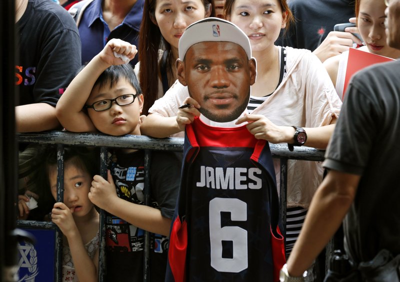 A fan of NBA star LeBron James holds a picture of James during a promotional event at a shopping district in Hong Kong as part of his China tour Wednesday, July 23, 2014. Earlier this month, James left the Miami Heat after four seasons and four trips to the NBA Finals and re-signed with the Cavaliers, where his career began. 