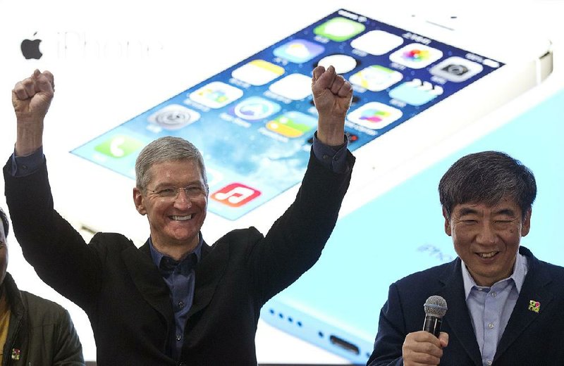 FILE - In this Jan. 17, 2014 file photo, Apple's CEO Tim Cook, left, gestures as China Mobile Chairman Xi Guohua smiles during a promotional event that marks the opening day of sales of China Mobile's 4G iPhone 5s and iPhone 5c in Beijing, China. Soaring sales of iPhones in China, Russia, India and Brazil during the April-June 2014 period helped Apple overcome softening demand for the device in the U.S. and Europe, where consumers seem to be more interested in waiting for the autumn release of a new iPhone that's expected to feature a larger screen. (AP Photo/Alexander F. Yuan, File)