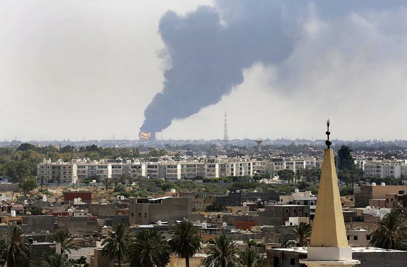 Black smoke billows over the skyline as a fire at the oil depot for the airport rages out of control after being struck in the crossfire of warring militias battling for control of the airfield, in Tripoli, Libya Monday, July 28, 2014. The latest violence to plague the country has so far killed scores of people and wounded hundreds as foreigners flee the chaos. Libya's interim government said in a statement that the fire could trigger a "humanitarian and environmental disaster" in Tripoli, appealing for "international help" to extinguish the inferno. (AP Photo/Mohammed Ben Khalifa)